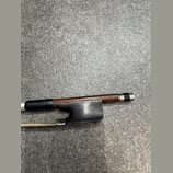 Detail smyčce s hnědým dřevěným tětivem a černým koženým omotem v rukojeti. Na dřevě je viditelný nápis G. ANDOVER. Konec smyčce je zakončen kovovým…