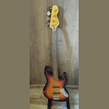 Elektrická basová kytara s korpusem v barevném přechodu od černé přes oranžovou k žluté (sunburst). Na hlavě hmatníku je nápis "Wilkinson ICON Series…