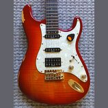 Elektrická kytara s červeně-žlutým sunburst povrchem a bílým perleťovým pickguardem. Na tříech snímačích je uveden nápis LEVINSON. Kytara má zlatý ha…