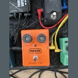 Kytarový efekt pedál oranžové barvy s nápisy MXR a phase 100. Na horní straně jsou dva černé oválové knoflíky s popisky INTENSITY a SPEED. V dolní čá…