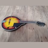 Akustická mandolina s hruškovitým korpusem v červeno-žlutém přechodovém lakování (sunburst). Na hlavě hmatníku je viditelný nápis "Saga". Nástroj má…