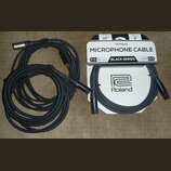 Černý mikrofonní kabel s XLR konektory, sbalený do dvou smyček. Vedle kabelu je bílé originální balení s nápisy MICROPHONE CABLE, BLACK SERIES, Rolan…