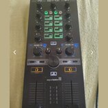 Černý DJ kontrolér s nápisem MDD-10R v horní části a logem algoriddim ve spodní polovině. Zařízení obsahuje několik otočných knoflíků, posuvníků a řa…