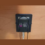Černý plastový bezdrátový vysílač s připojeným mikrofonem. Na spodní straně je fialová nálepka s nápisy PT 40 FLEXX, Band 40/G, ch1 812.700 MHz, ch2…