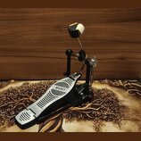 Černý basový pedál s kovovou stoupací deskou. Na desce je umístěno logo MAPEX v oválném rámečku s bodovaným pozadím. Pedál je vybaven kovovým mechani…