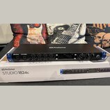 Černý rackový zvukový interface PreSonus STUDIO 1824c s modrými bočními elementy. Na předním panelu jsou umístěny ovládací knofíky, dva kombinované v…