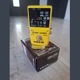 Žlutý loop pedal NUX LOOP CORE umístěný na své originální krabici. Zařízení má černý ovládací panel s nápisy USB, DC 9V, SAVE DELETE, STOP MODES a RH…