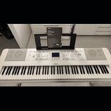 Bílá digitální klaviatura značky YAMAHA, model DGX-660. Nástroj má v horní části ovládací panel s displejem, tlačítky a knoflíky, vpravo je nápis Dig…