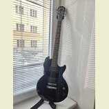 Tmavě modrá elektrická kytara typu Les Paul s černým hmatníkem a stříbrným hardwarem. Na hlavě je bílý nápis Epiphone a logo Spiral. Kytara má dva hu…
