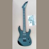 Černá elektrická kytara s typickým špičatým hřátem, na kterém je bílý nápis Jackson. Nástroj má dva humbuckery, strunovou kotvu a černý hardware. Ved…