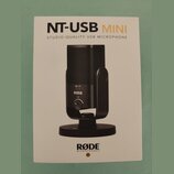 Fotografie znázorňuje produktový manuál nebo obal k mikrofonu. Je na něm zobrazen černý kondenzátorový mikrofon na stojanu s nápisy NT-USB MINI a STU…