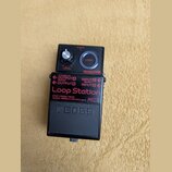 Černý efekt pedál značky BOSS s nápisem Loop Station a označením modelu RC-1. Horní panel obsahuje ovládací knob LEVEL, červené tlačítko LOOP a tlačí…