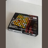 Krabice s MIDI kontrolérem Novation Launchpad Mini. Na povrchu je zobrazen produkt s podsvícenými pady a nápisy LAUNCHPAD MINI, novation, The mini gr…
