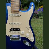 Modrá elektrická kytara s krémovým pickguardem a hnedým hmatníkem. Na snímačích jsou nápisy NOISELESS a na prostředním snímači je viditelné logo Fend…