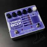 Fialový efekt pedál s bílým nápisem VOICE BOX a podtitulem harmony machine and vocoder. Na spodní části je uveden výrobce electro-harmonix a nápis MA…
