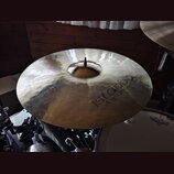 Zlatavý činel s viditelným broušením povrchu. Na pravé straně je nápis istanbul Agop Handmade Turkey. V horní části je vyryto trojúhelníkové logo. Či…