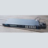 Černý rackový bubnový modul s nápisem ALESIS DM5 a doplňkem HIGH SAMPLE RATE 16 BIT DRUM MODULE. Zařízení má malý displej, jeden ovratový ovládací kn…