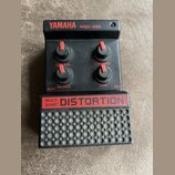 Černý efekt pedál s nápisy YAMAHA MBD-20M a MULTI BAND DISTORTION. Zařízení má tři červené otočné knoflíky s popisky OUT LEVEL, BALANCE a TONE, přiče…