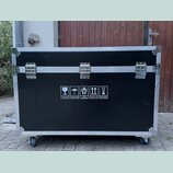 Černý transportní flightcase s hliníkovými hranami a kovovými rohy. Přední strana obsahuje tři stříbrné zapínací zámky a bílé informační piktogramy s…
