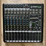 Černý 12kanálový mixážní pult s nápisem ProFX12 PROFESSIONAL EFFECTS MIXER. Zařízení obsahuje řadu vstupních kanálů s ovládacími knofíky, posuvníky a…