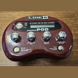 Vínový efektový procesor s nápisy LINE 6 a pocket POD. Zařízení má čtyři chromované otočné ovladače s popisky EFFECTS MID, DELAY TREBLE a CHAN VOL RE…