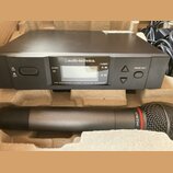Černý bezdrátový přijímač s nápisem audio-technica. a označením UHF SYNTHESIZED DIVERSITY RECEIVER ATW-R3100. Obsahuje displej, tlačítka POWER a MODE…
