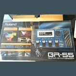 Fotografie znázorňuje krabici od kytarového syntetizátoru s nápisem Roland GR-55 GUITAR SYNTHESIZER. Na obalu je zobrazen modrý přístroj s displejem,…