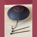 Černý kovový tongue drum s dekorativním ornamentem v horní části. Na povrchu je bílý nápis „Sonic Energy“ a nad ním logo znázornující dvě stylizované…