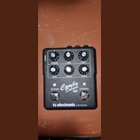Černý kytarový předzesilovač s bílým předním panelem. Na panelu jsou šest otočných ovladačů s popisky REVERB, GAIN, LEVEL, BASS, MIDDLE a TREBLE, dva…