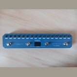 Modrý efektový pedál s kovovým povrchem. Na horní hraně se nachází řada černých oválečných tlačítek s popisky: MASTER, LEVEL, REVERB, TIME, DELAY, RA…