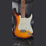 Elektrická kytara s korpusem v barevném přechodu od tmavě hnědé k žluté. Nástroj má bílý perleťový pickguard, tři snímače s bílými plastovými kryty a…