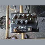 Černý kytarový pedál s nápisy MXR a bass d.i.+ . Zařízení obsahuje pět otočných potenciometrů s popisky BASS, MID, TREBLE, GAIN a GATE, dva zapínací…