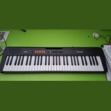 Černý elektronický klavír s bílými a černými klávesami. Na levé straně je bílé logo CASIO a na pravé straně nápis CasioTone CT-S100. V horní části se…