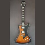 Elektrická kytara s trupem v barevnosti sunburst a černým pickguardem. Na hlavě hmatníku je bílé logo Hagstrom a na zadní straně krku je viditelné sé…