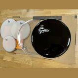 Sada bubenových koží položená na kartonovém podkladu. Na bílých a průhledné kožem jsou viditelná loga Gretsch. Největší černá koža nese bílé logo Gre…