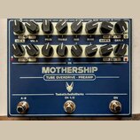 Modrý rackový efekt s nápisy MOTHERSHIP a TUBE OVERDRIVE - PREAMP. Na spodní části je logo s hlavou zvířete a text TsakalisAudioWorks CH 1/2. Zařízen…