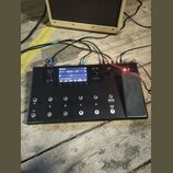 Černý kytarový procesor s displejem a řadou spínačů. Na displeji je vidět nápis G1A Evo a v dolní části text 1. Electro Harmonix Drive. Zařízení má č…