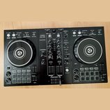 Černý DJ kontrolér Pioneer DJ DDJ-400. Na přístroji jsou viditelné nápisy PERFORMANCE DJ CONTROLLER, DDJ-400 a logo rekordbox. Zařízení obsahuje dva…