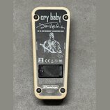 Zadní strana efekt pedálu s krémovým rámem a černým kovovým krytem. Na krytu je bílý nápis cry baby, podpis Jimi Hendrix a text JH-1B JIMI HENDRIX SI…