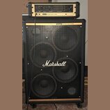 Černý basový kombozesilovač tvořený hlavou a reproboxem. Na obou částech je nápis Marshall DYNAMIC BASS SYSTEM a na přední mřížce boxu velké bílé log…