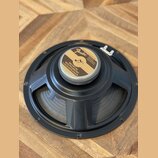 Černý reproduktor s kovovým rámem a papírovou membránou. Uprostřed je štítkem s nápisy „Fender“, „SPECIALLY DESIGNED FOR FENDER INSTRUMENTS CORPORATI…