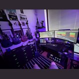 Fotografie zachycuje hudební studio s několika elektrickými kytarami. Na stěně jsou zavěšeny čtyři kytary, z nichž tři jsou černé a jedna červená; na…
