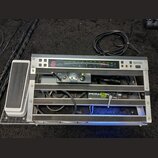 Stříbrný rackový systém s černými vložkami, který obsahuje několik zařízení a kabeláže. V horní části je panel s digitálním displejem zobrazujícím če…