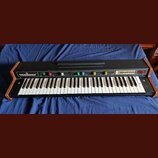 Černý elektronický klávesový nástroj s dřevěnými bočními panely. Na levé straně ovládacího panelu je bílý nápis VERMONA a vpravo nápis PIANO. Nástroj…