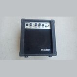 Černý malý kytarový kombo zesilovač s bílým ovládacím panelem. Na panelu jsou nápisy REEF AUDIO, LA5, INPUT, GAIN, VOLUME, TONE, PHONES a DC9V. Na sp…