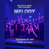 Fotografie zobrazuje skupinu lidí v černých tričkách s bílým nápisem „ROCKOVÝ SBOR PRO DOSPĚLÉ MELODY“. Snímek je pořízen v interiéru s výrazným modr…