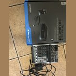 Na fotografii je modrá krabice s nápisy WIRELESS HEADMIC SET, EASY TO USE, EXCELLENT FOR LIVE SOUND a XS WIRELESS 1 spolu s logem SENNHEISER. Pod kra…