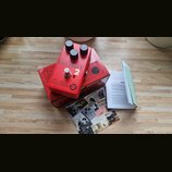 Červený kytarový efekt s třemi černými oválnými knoflíky. Na horní straně je nápis BIG MUFF a bílá číslice 2, níže se nachází logo electro-harmonix s…