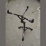 Černý skládací stojan na noty z kovového materiálu. Stojan má trojnožku a rozkládací horní část s opěrnými rameny. Na povrchu nejsou viditelné žádné…
