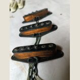 Tři elektrické snímače typu single-coil s oranžovými cívkami a černými plastovými základnami. Snímače mají kovové pólové šrouby a jsou připojeny k če…